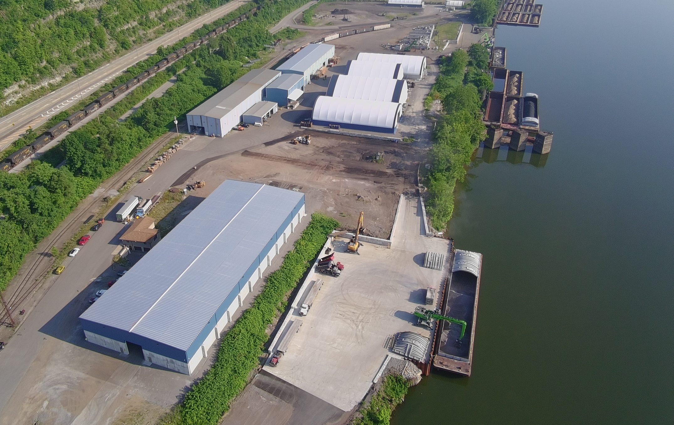 Aerial view of the terminal warehouses, the dock, and barges on the Ohio River, with rail lines along the hillside.
