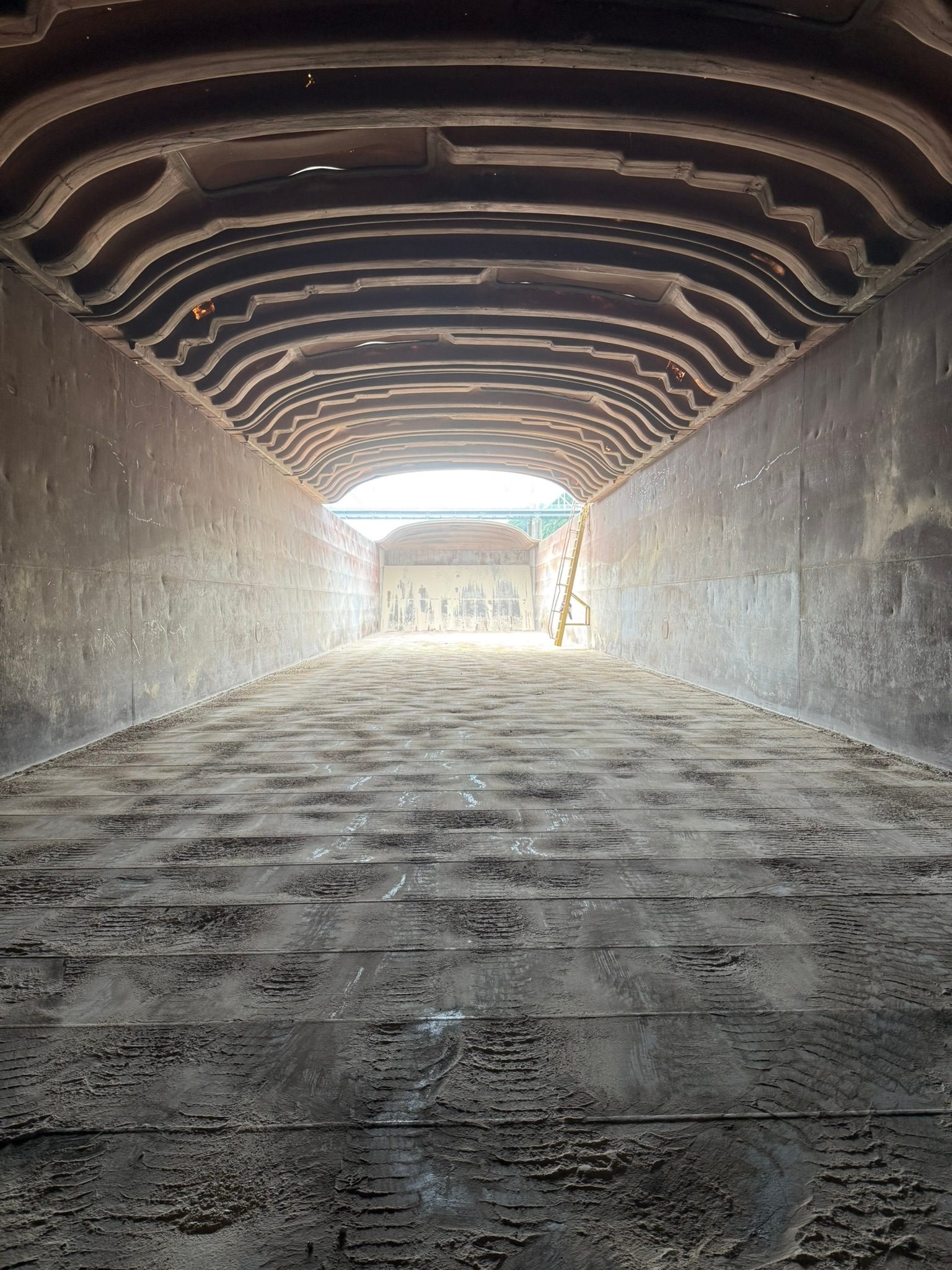 Looking down the length of an empty covered barge from inside the hold toward the open end.